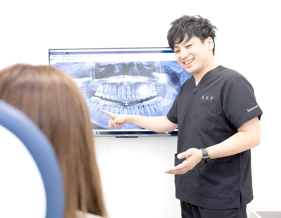 レントゲン画像を見ながら治療内容を説明する歯科医師